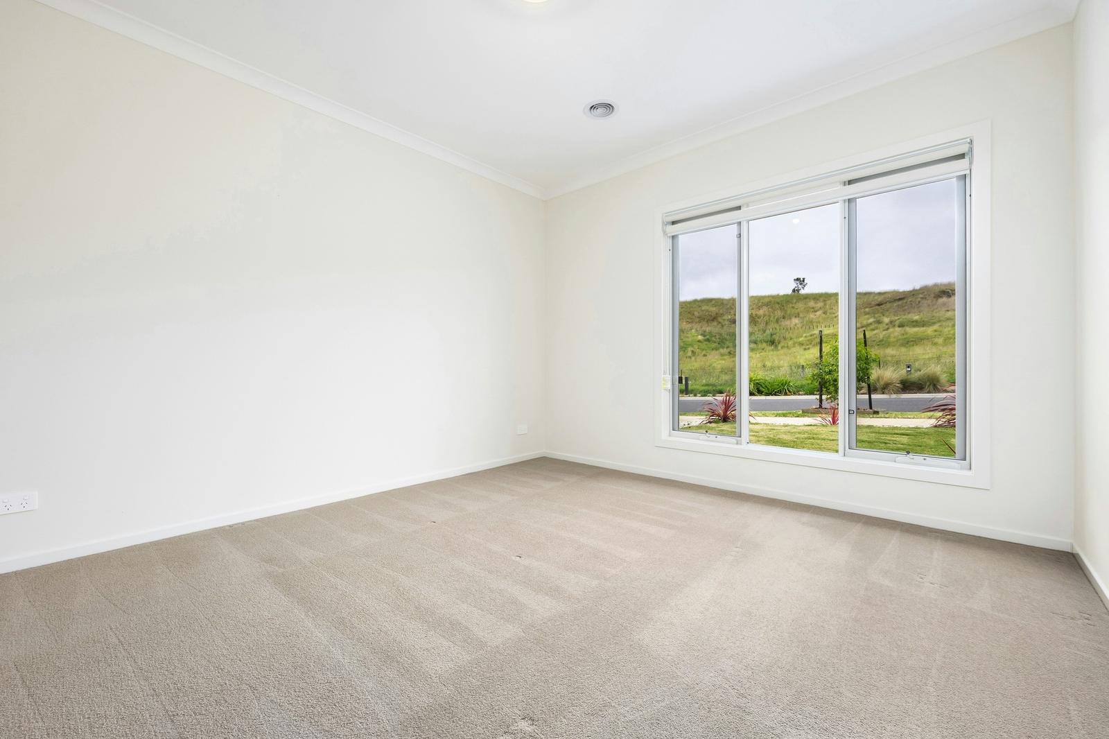 Empty primary bedroom with white walls and carpet